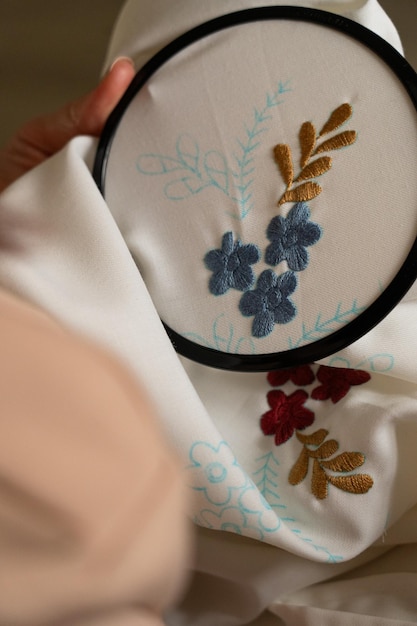 Mâini care brodează un model floral